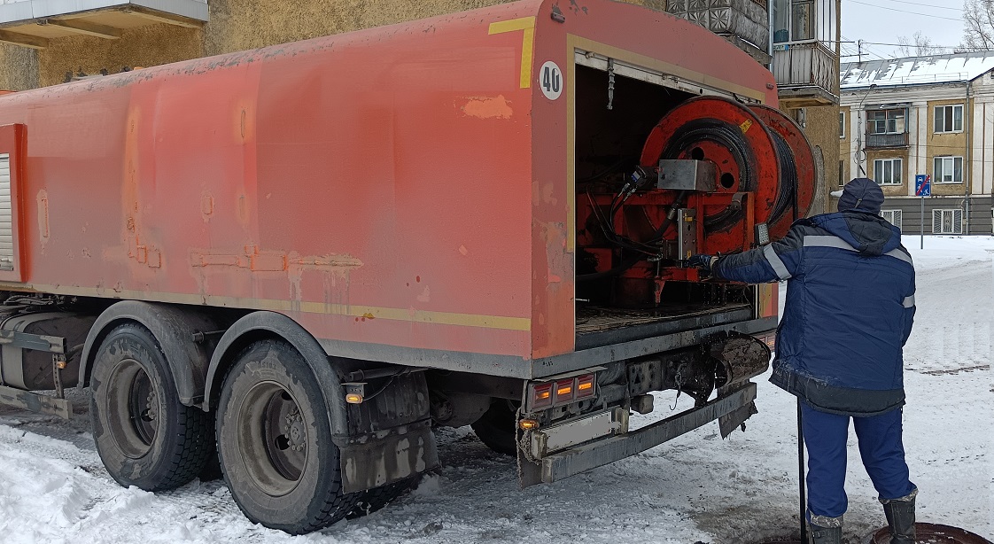 Каналопромывочная машина и работник прочищают засор в канализационной системе в Рыбном